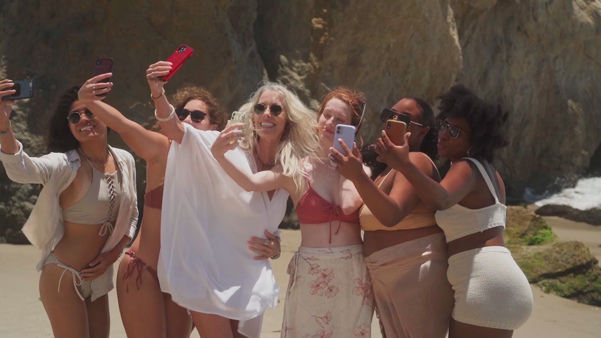 Women on a beach taking selfies